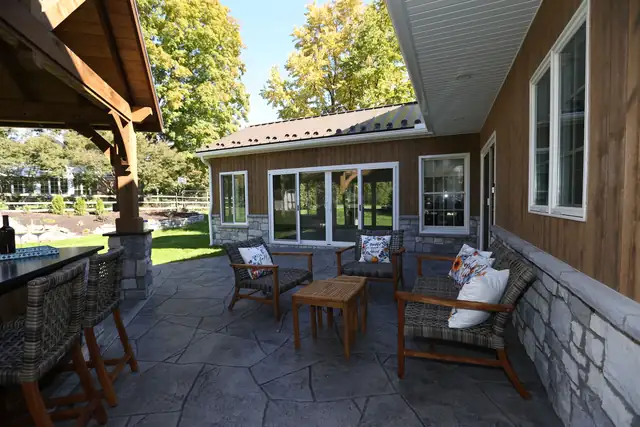 Stamped concrete patio and outdoor kitchen beside a four-seasons room addition in Lancaster, PA